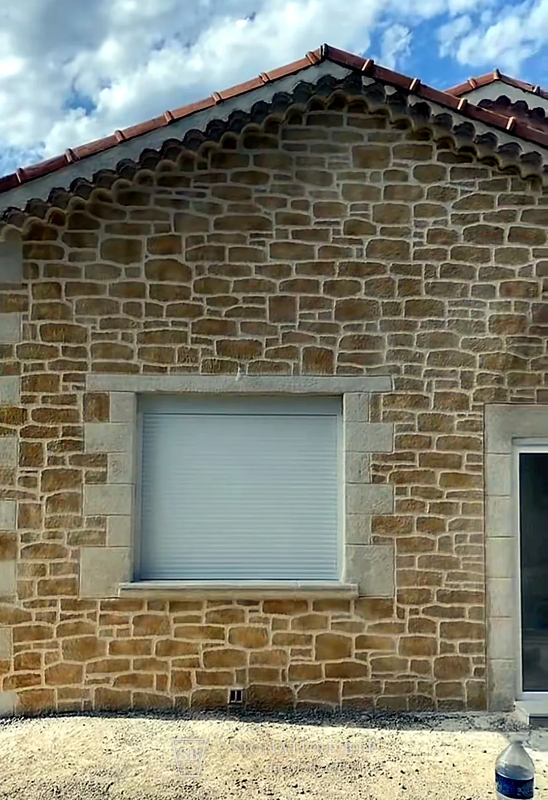 Pignon de maison en enduit sculpté pierre dorée avec encadrements de fenêtres