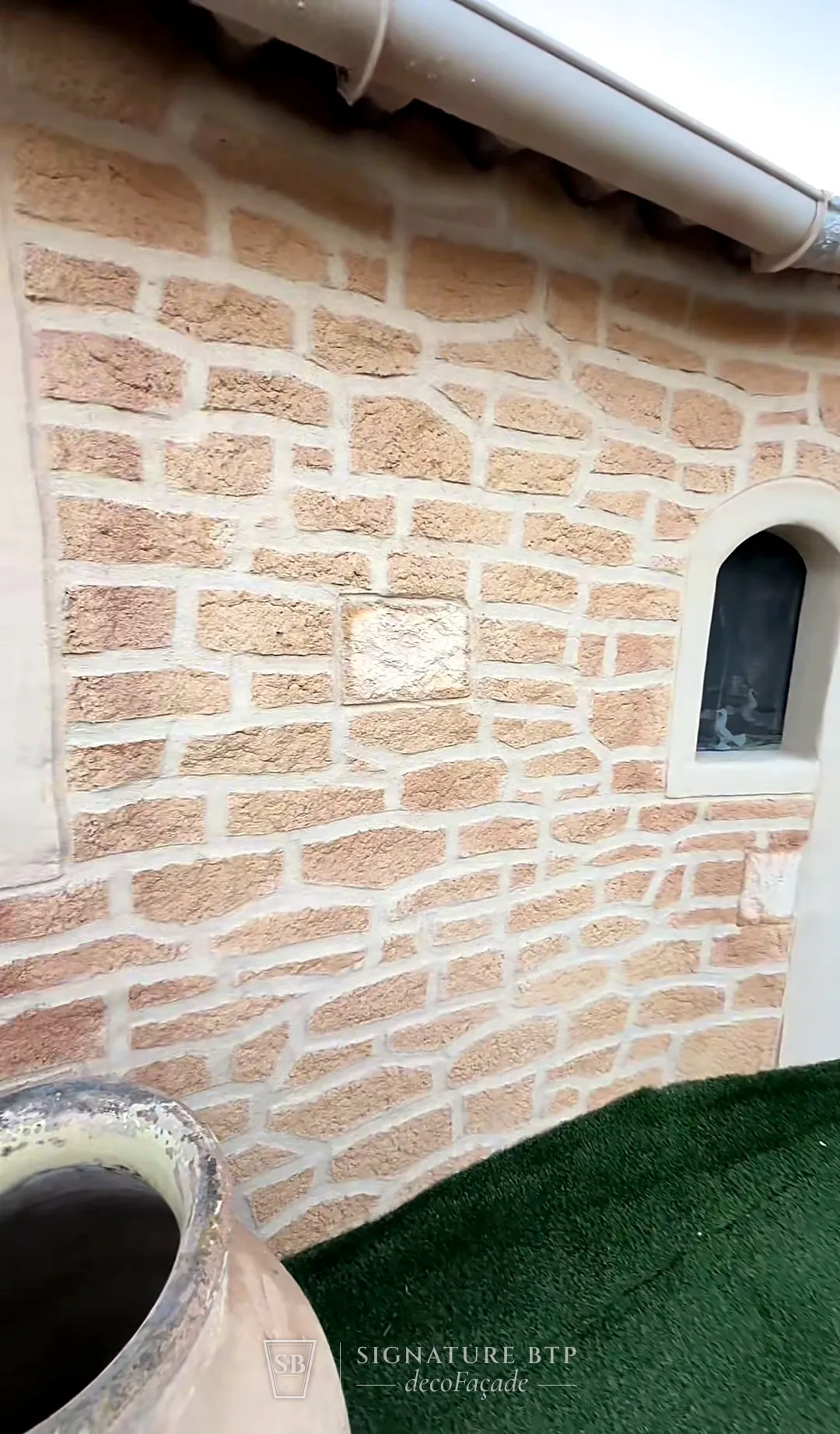 Mur en pierres claires sculptées avec une petite fenêtre en arche