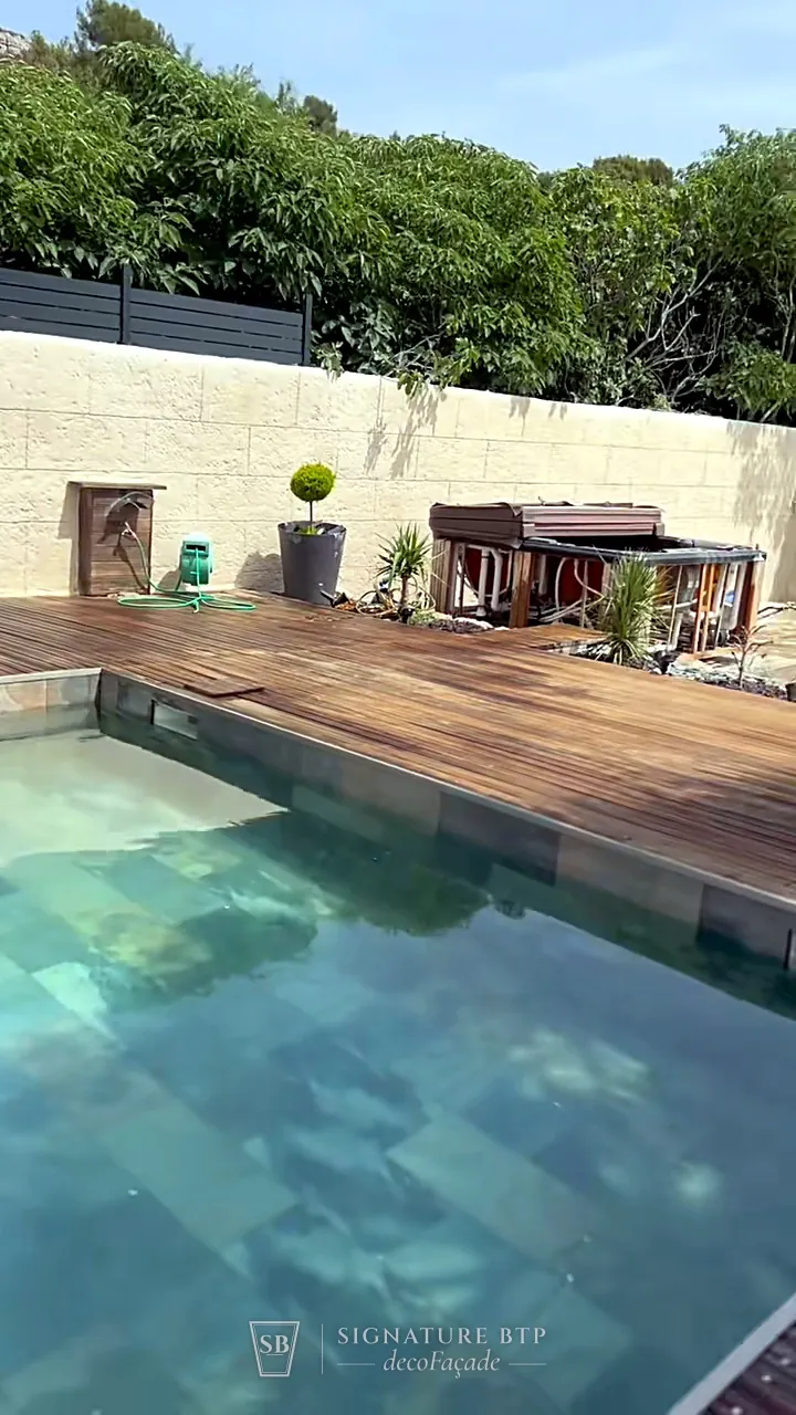 Mur en pierre de taille au bord d’une piscine avec terrasse en bois
